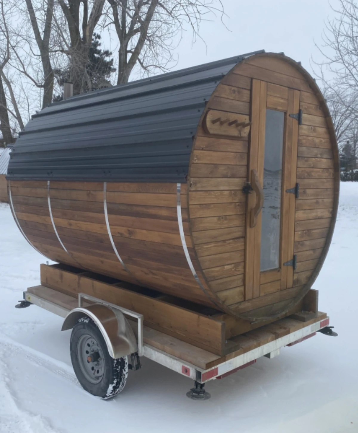 SaunaSpa.Ca Mobile Barrel Sauna on a trailer in a snowy outdoor setting